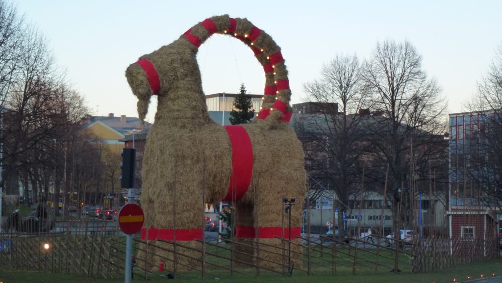 En julbock i halm med röda band