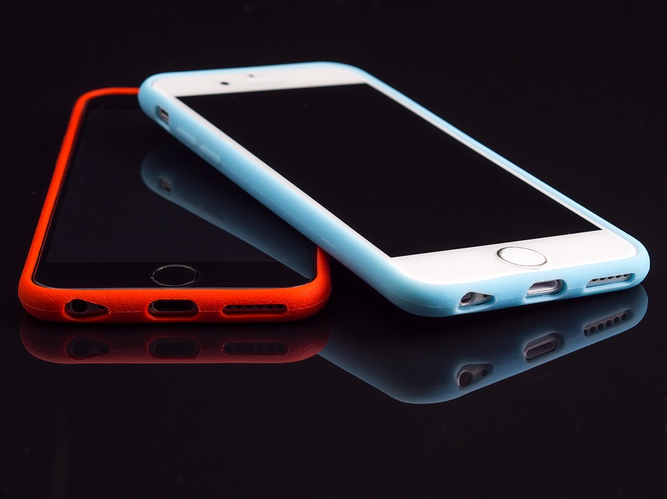 Två iPhones en med ett rött fodral och en med ett vitt fodral.