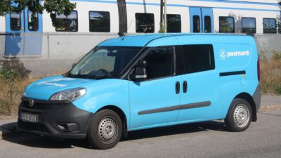 En ljusblå Postnord bil