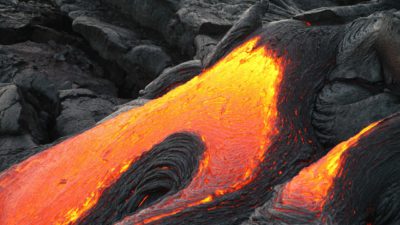 Eldig lava som rinner med svart stelnad lava runt omkring