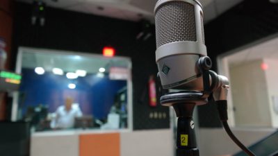 En mikrofon med en radiostudio i bakgrunden