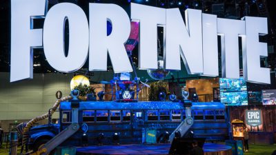 Stora bokstäver som bildar ordet Fortnite hänger ovanför en gammal buss.