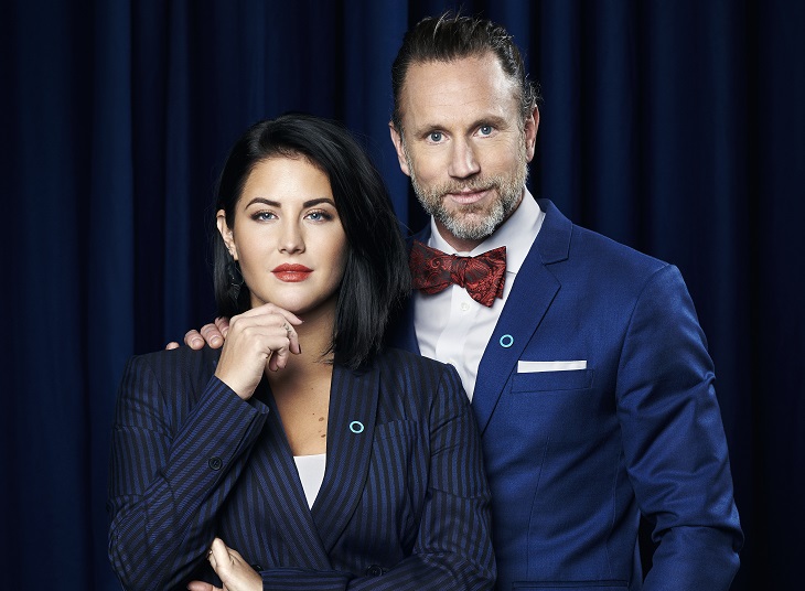 Peter Jihde har blå kavaj och röd slips. Han har lagt sin hand på Mollys axel. Molly har en blårandig kostym och håller ena handen lyft till hakan.