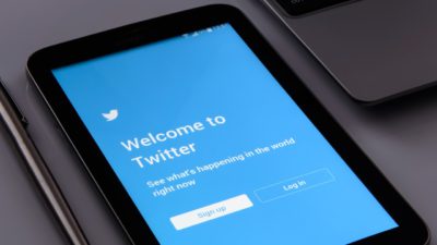 Bild på en surfplatta som ligger på ett bord. På surfplattan syns förstasidan till Twitter.