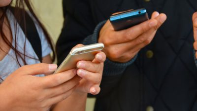 Två personer som håller i varsinn smartphone